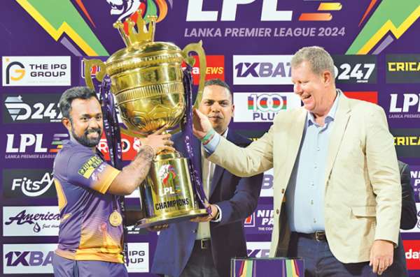 Jaffna Kings skipper Charith Asalanka receving LPL champions trophy from Sports Minister Harin Fernando and ICC Chairman Greg Barclay while Tournament Director Samantha Dodanwela looks